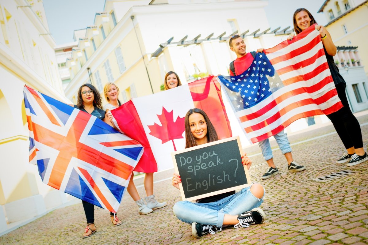 Grupo de estudiantes sonrientes con banderas de Reino Unido, Canadá y Estados Unidos
