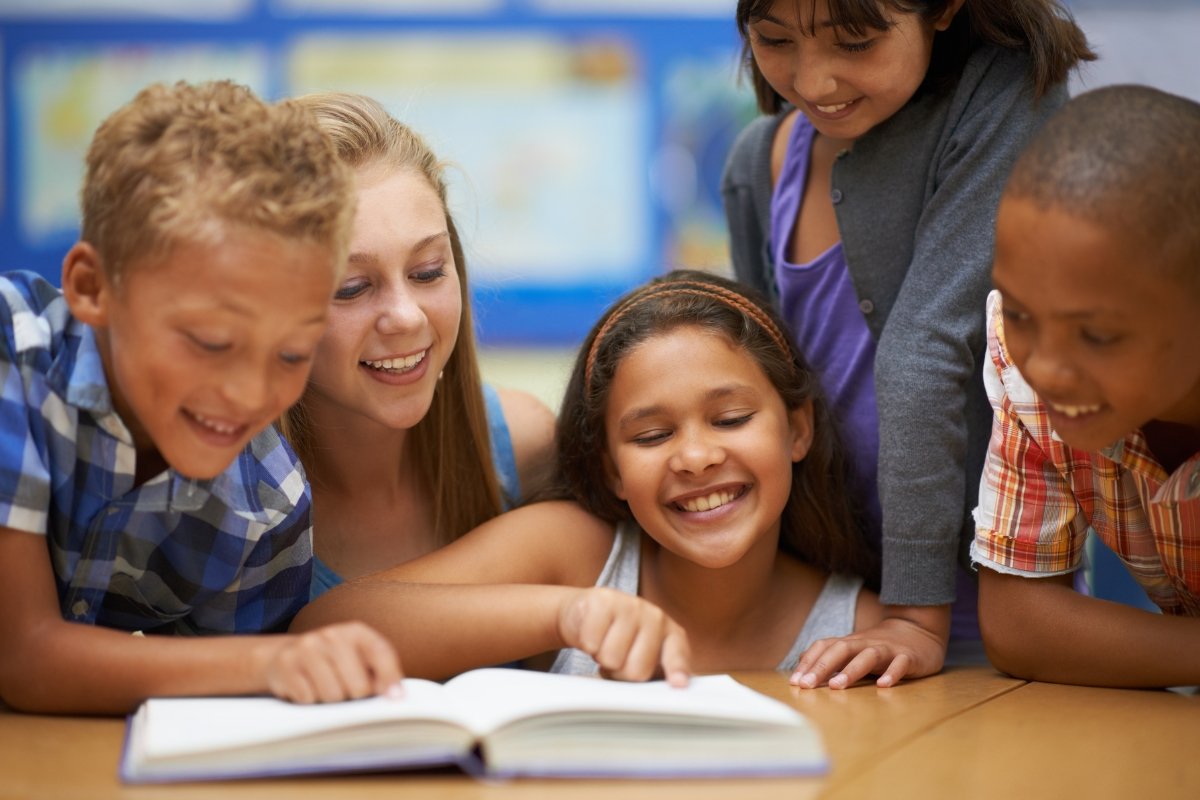 Niños sonrientes leyendo juntos un libro en el aula